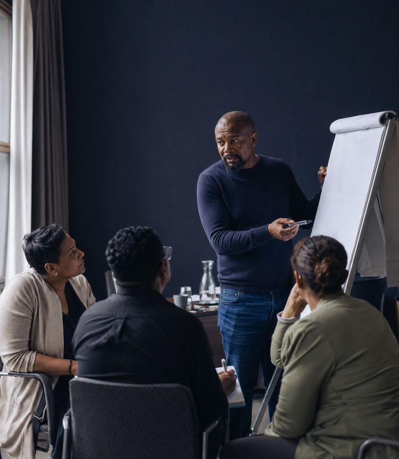 A first-line manager presenting at a flipchart while colleagues listen