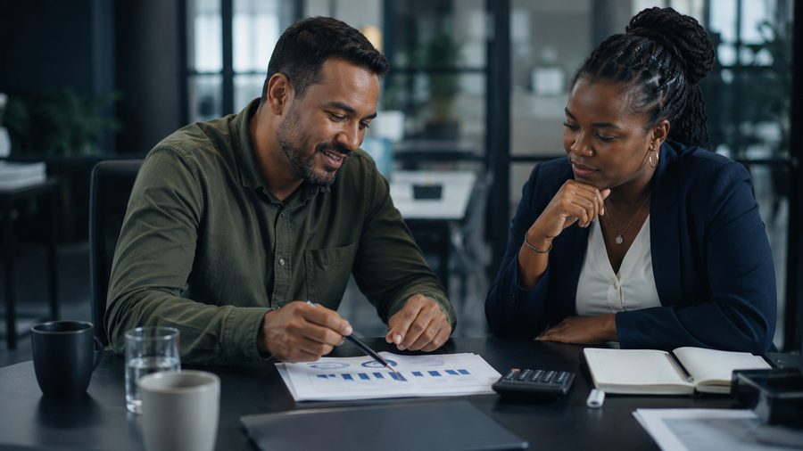 A manager and colleague working through a simple chart with a calculator