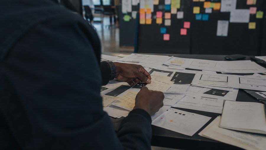 Hands arranging paper prototypes on a work table
